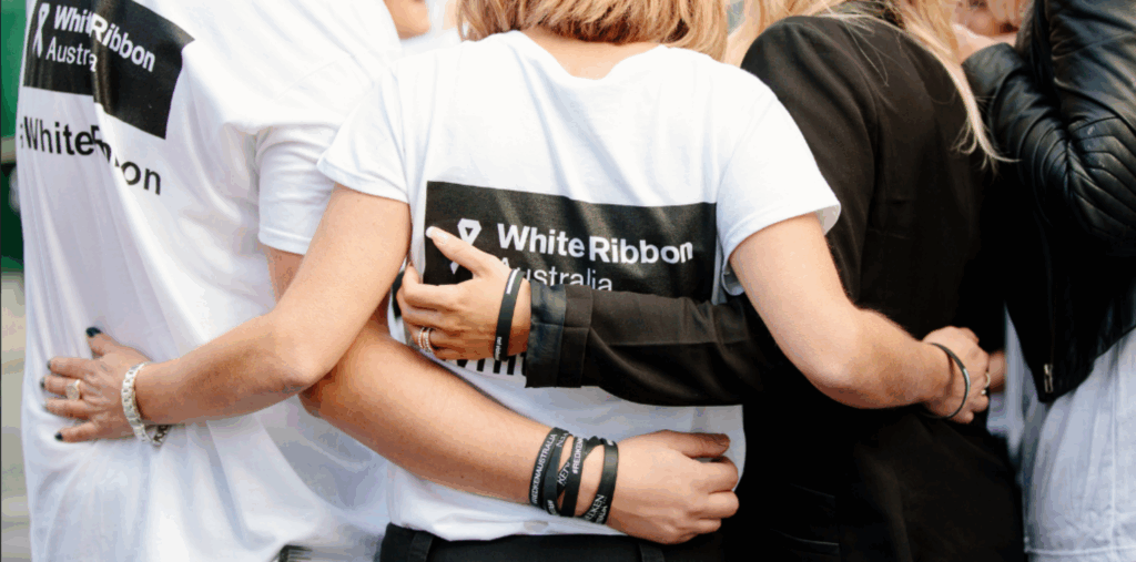 A group hug of people in White Ribbon Australia t-shirts